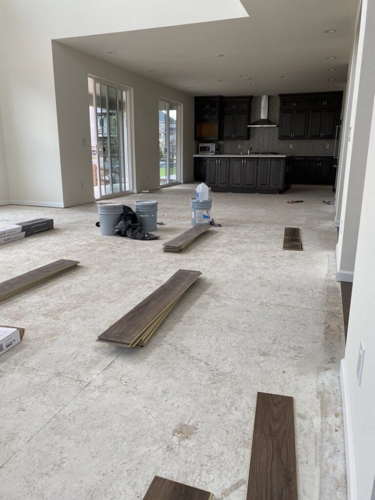 Floor repair or installation in progress, showing exposed joists, pipes, and new floorboards by IHS flooring LLC in Brighton, CO.