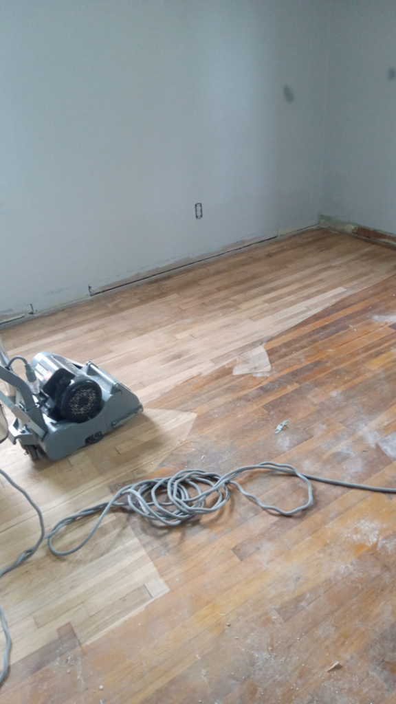 A floor sander in use, refinishing a wooden floor for Charles and Drew Project Page in Detroit, MI.