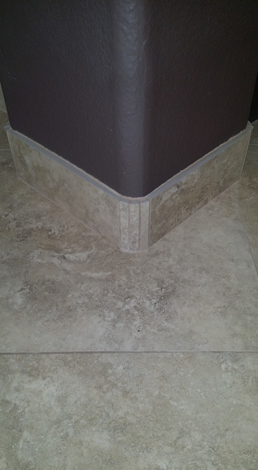 Newly installed floor tiles with decorative baseboard trim by Gudiño's Tile and Natural Stone in Glendale, AZ