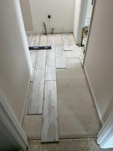 Floor tile installation in progress with a level tool, demonstrating a handyman service by Worths handyman services in Wasilla, AK.