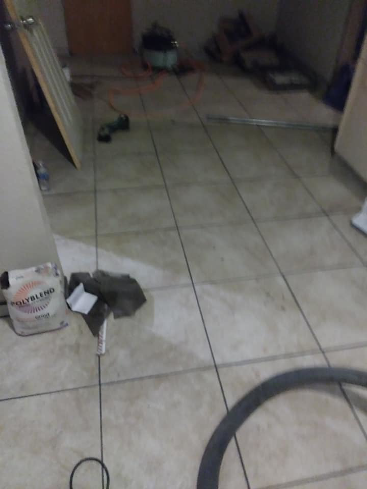 A floor tiling project in progress with tools and grout visible by TaylorMade handyman services in Roswell, NM