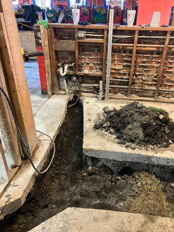 Floor trenching and an exposed brick wall visible during a renovation project by JB Renovations in Houston, TX.