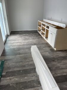 Wood-look vinyl plank flooring and base cabinets being installed in a room by Creative Carpets in North Las Vegas, NV.