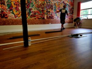 A worker from Stormtroopers Home Improvement installing wood-look flooring in a vibrant commercial space in Port St. Lucie, FL.