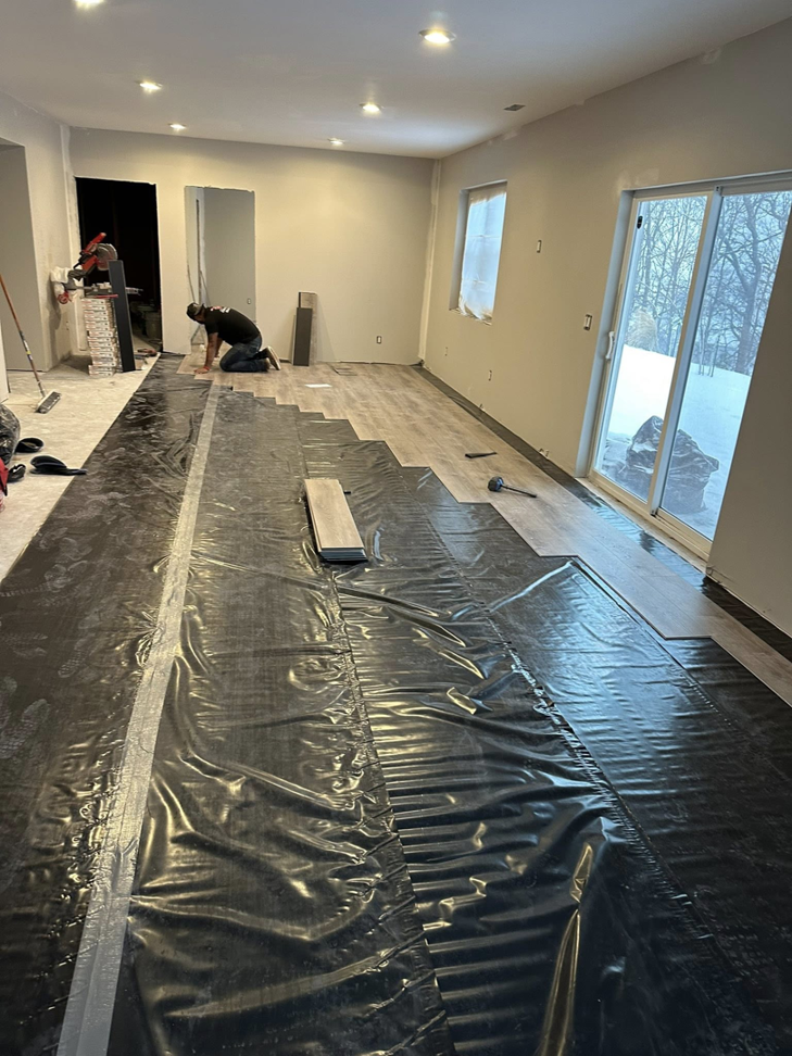 A handyman installing new flooring in a residential room, a service provided by Tri Lake Construction in Madison, WI