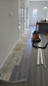 New flooring installation in progress in a hallway, with a shop vacuum and trim pieces, by Kirkland Residential & Property Solutions in Clarksville, TN