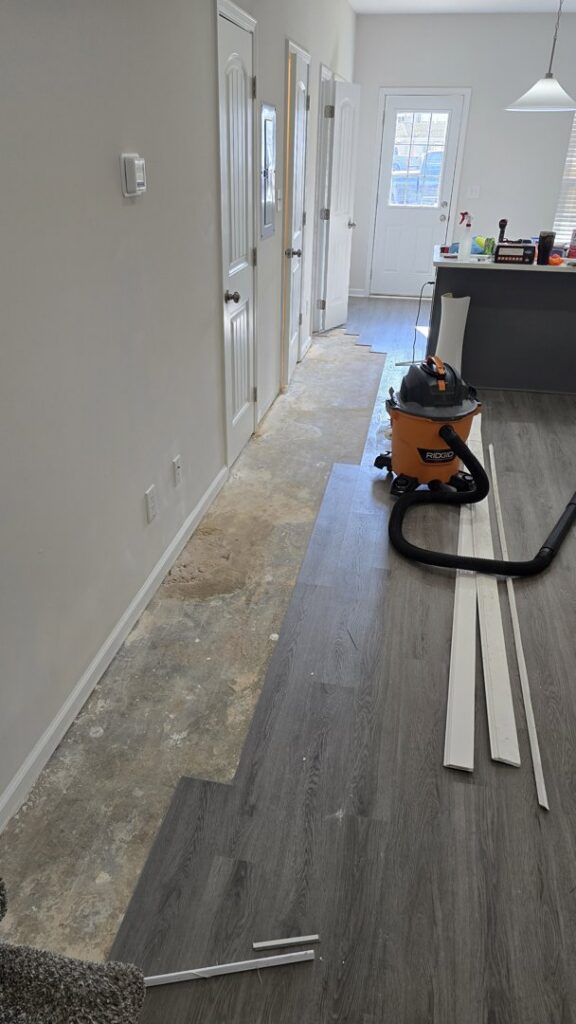 New flooring installation in progress in a hallway, with a shop vacuum and trim pieces, by Kirkland Residential & Property Solutions in Clarksville, TN