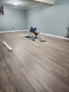 Wood-look vinyl plank flooring installation in progress with a miter saw and tools by Creative Carpets in North Las Vegas, NV.