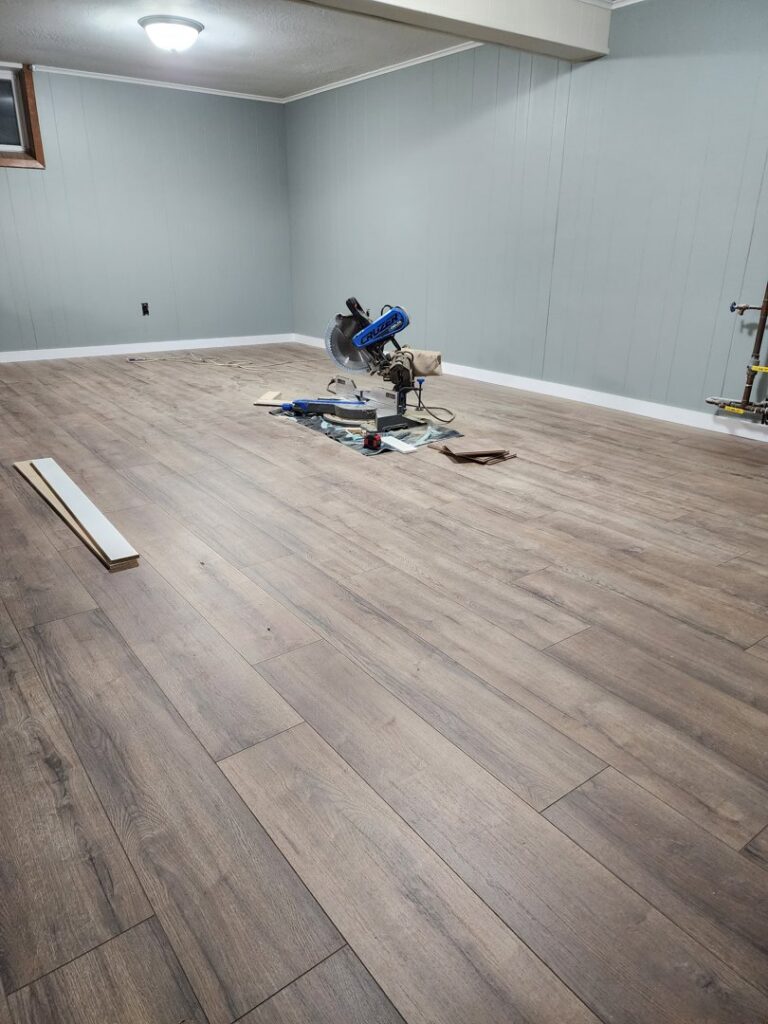 Wood-look vinyl plank flooring installation in progress with a miter saw and tools by Creative Carpets in North Las Vegas, NV.