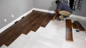 A professional installing new laminate wood flooring in a room, a quality service provided by Rapid Response Crew in Charlotte, NC.