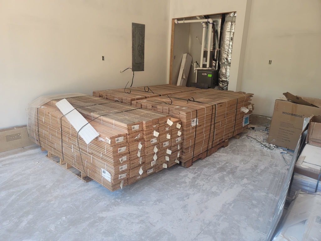 Stacks of new flooring materials on pallets inside a construction site by RRC Reign Roofing & Construction in Oklahoma City, OK.