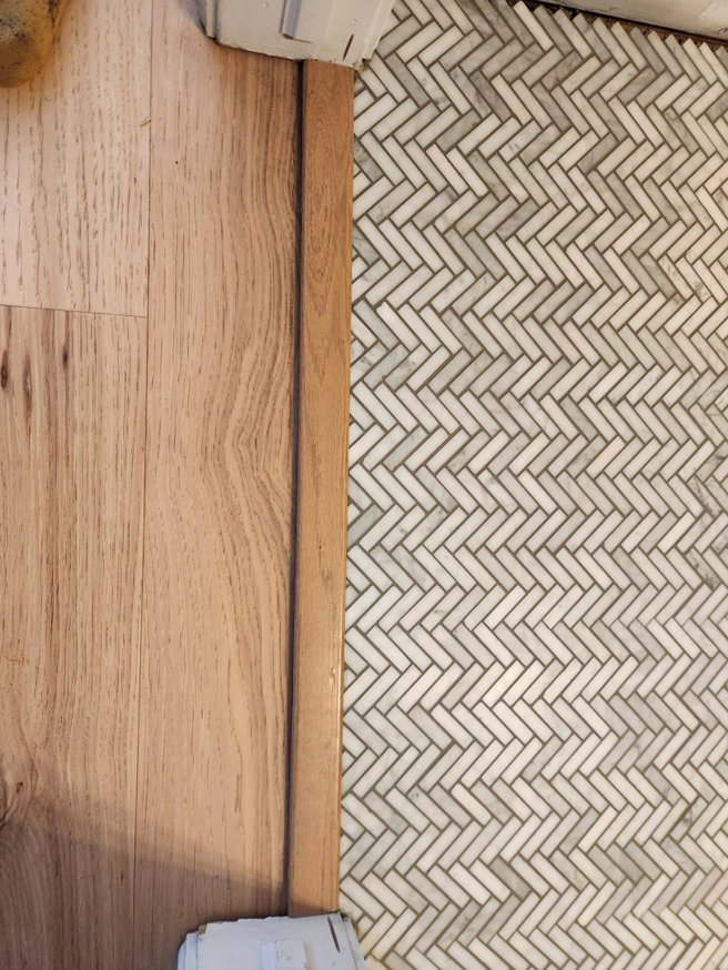 Newly installed flooring transition strip between hardwood and tile by SG Service, LLC in Lincoln, NE