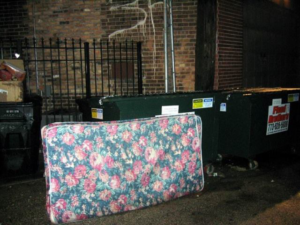 A floral mattress left next to dumpsters, ready for pickup by Omaha junk Removal and Hauling Service in Omaha, NE.
