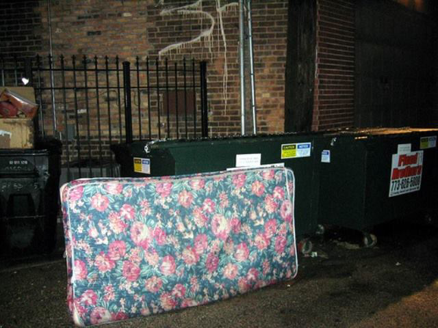 A floral mattress left next to dumpsters, ready for pickup by Omaha junk Removal and Hauling Service in Omaha, NE.