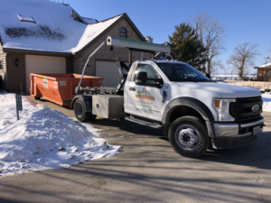 A City Disposal Services Inc. Ford truck delivering an orange roll-off dumpster to a residential driveway in Appleton, WI.