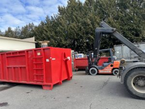 A forklift moving a red dumpster at the Cascade Container and Recycling yard in Seattle, WA.