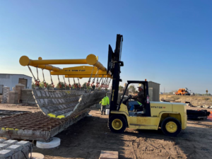 A forklift operator carefully moving a large precast concrete section at Arco Concrete Inc in Fort Lupton, CO