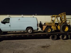 Forklift and van being hauled on a flatbed trailer by Jugganott Recycling, LLC in Orlando, FL.