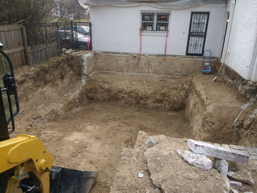 A large pit dug for foundation or basement excavation next to a residential building by Aspen Excavation in Spokane, WA.