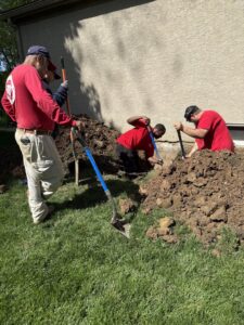 Workers excavating soil around a house foundation for repair by The Basement Doctor in Reynoldsburg, OH.
