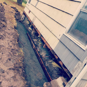 A trench dug alongside a house foundation for repair or drainage by KB Construction NW, Inc. in Springfield, OR.