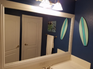 A beautifully framed bathroom mirror and new light fixture installed by Little Blue Handyman in Henderson, NV.