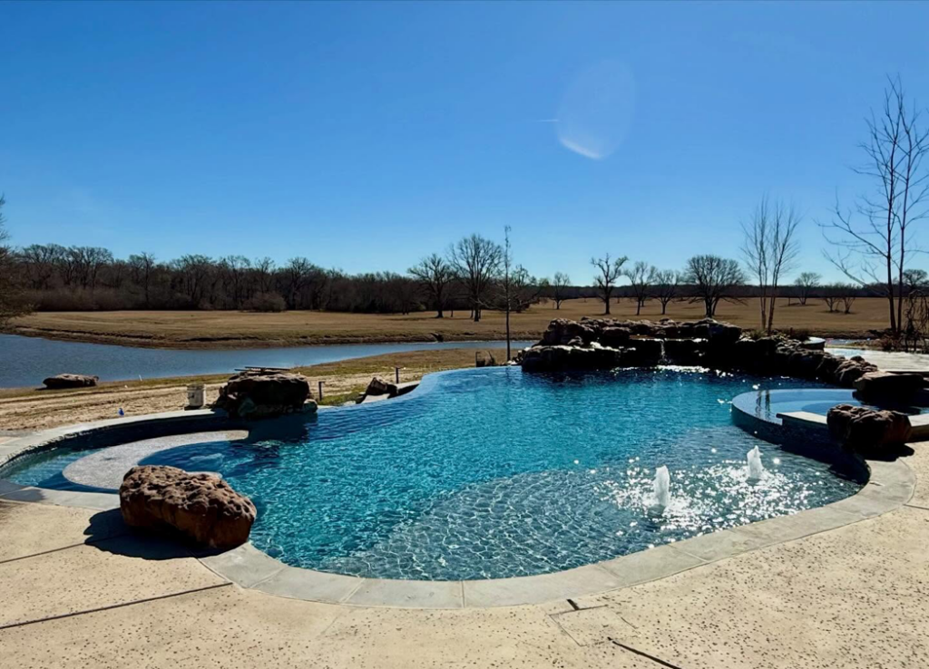 A stunning freeform pool with rock waterfall and spa built by First Class Pools & Spas in Sachse, TX.
