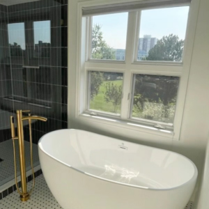 A newly installed freestanding bathtub with a modern gold faucet by Buerger Brothers Construction in Lakewood, CO.