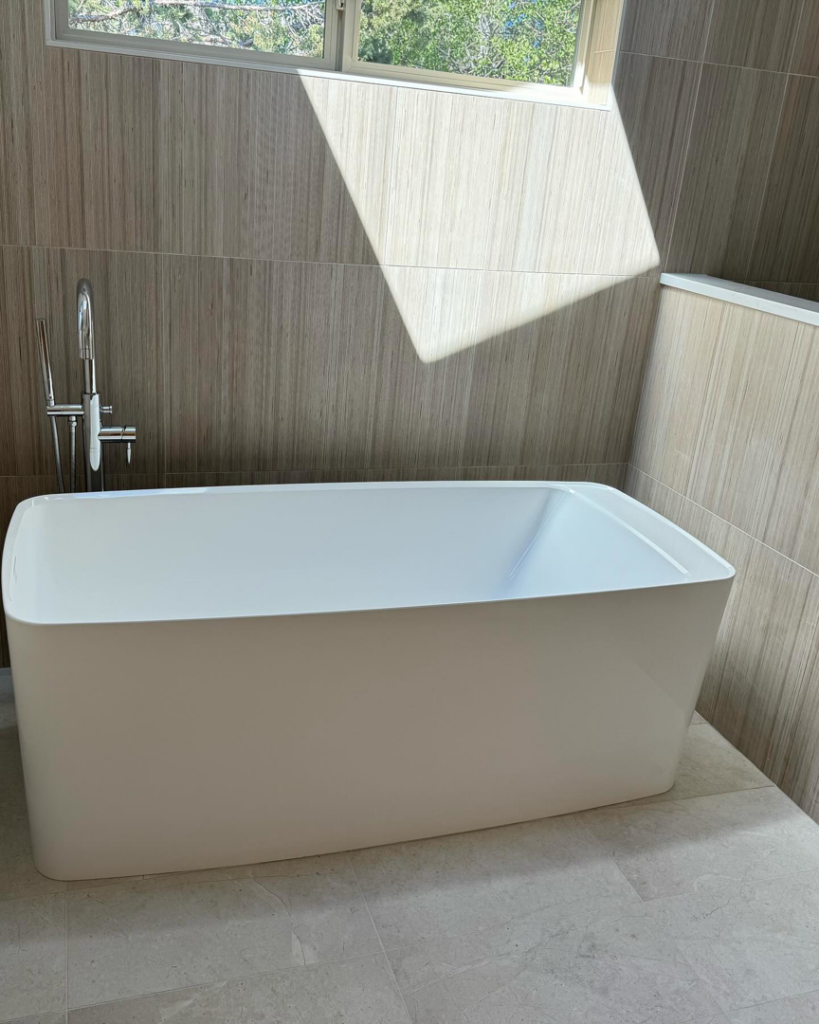 A freestanding bathtub and floor-mounted faucet installed with tiled walls by Nelson Tile and Stone in Bend, OR.