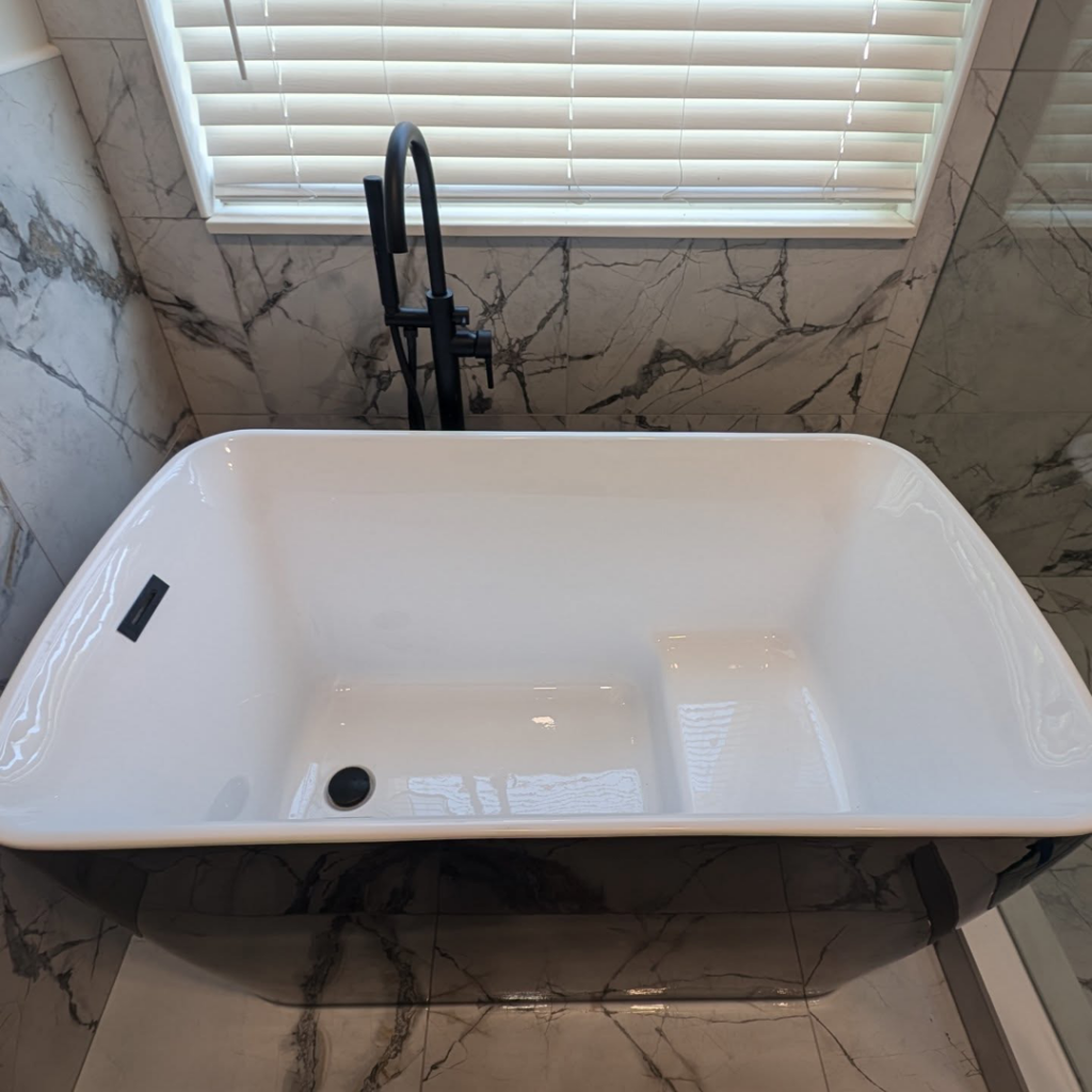 A stylish freestanding black and white bathtub with a black faucet installed by Ensotile - Atlanta Bathroom Remodeling in Stone Mountain, GA