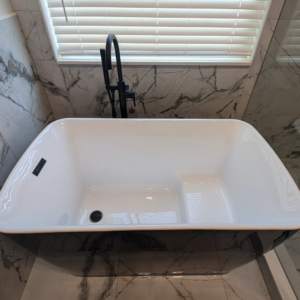 A stylish freestanding black and white bathtub with a black faucet installed by Ensotile - Atlanta Bathroom Remodeling in Stone Mountain, GA