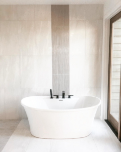A freestanding tub with black fixtures and a tiled accent wall installed by Nelson Tile and Stone in Bend, OR.