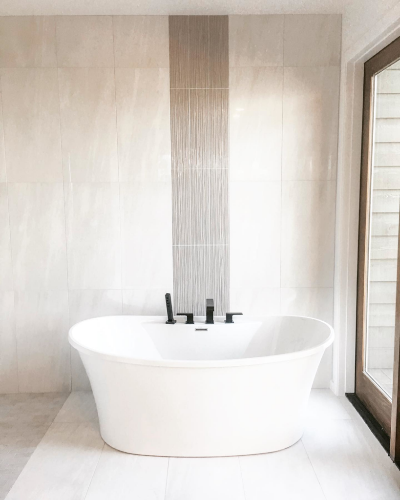 A freestanding tub with black fixtures and a tiled accent wall installed by Nelson Tile and Stone in Bend, OR.