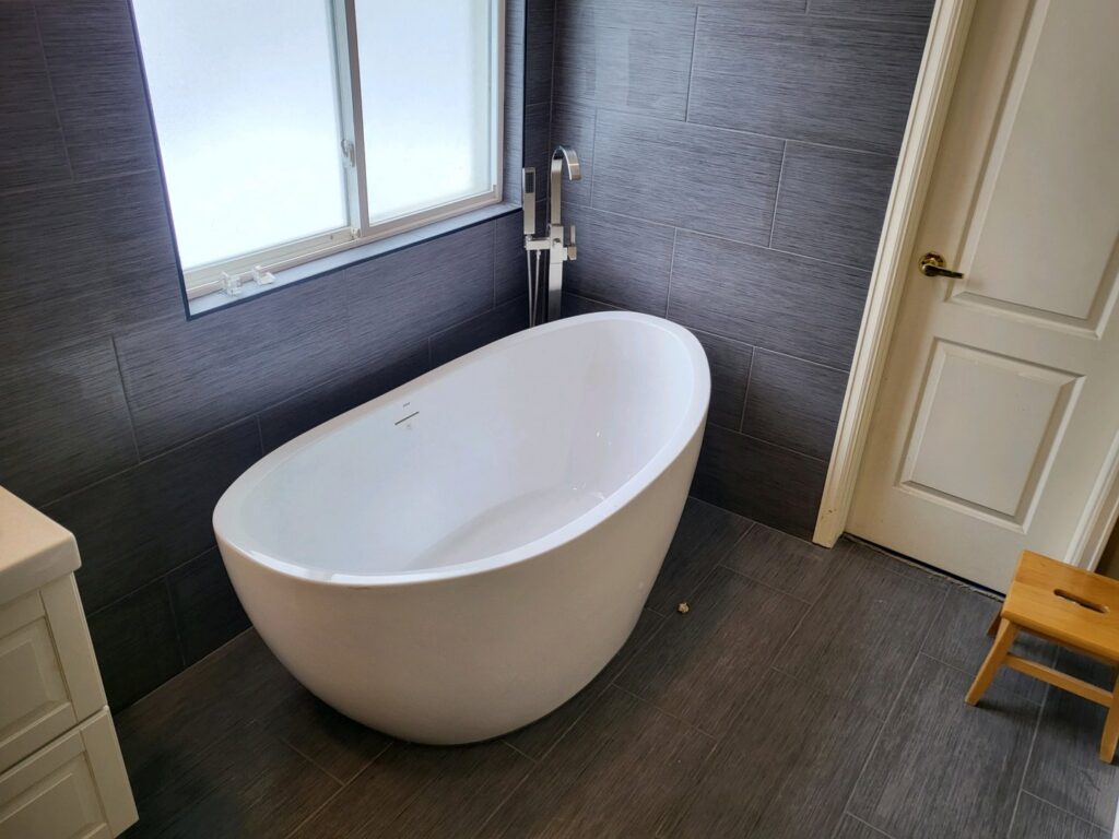 A modern freestanding bathtub with a floor-mounted faucet, installed as part of a bathroom renovation by Mr. Affordable LLC in Denver, CO.