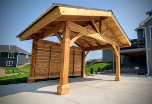 A freestanding wooden pergola with a solid roof and slatted side wall, constructed by Minnesota Pergolas in Lakeland, MN.