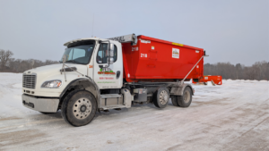 A City Disposal Services Inc. Freightliner truck with a red roll-off dumpster parked in a snowy field in Appleton, WI.