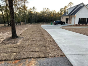 Freshly laid sod next to a concrete driveway and house by Stokes Contracting LLC in Mobile, AL