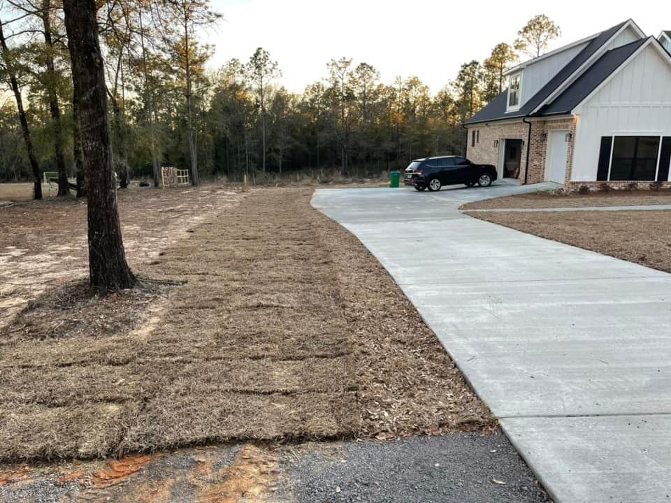 Freshly laid sod next to a concrete driveway and house by Stokes Contracting LLC in Mobile, AL