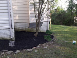 A freshly mulched garden bed along the side of a house, completed by C&C LAWN CARE,MOVING & TRASH REMOVAL in Baltimore, MD