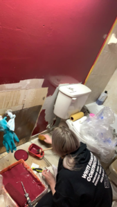A freshly painted red bathroom corner with masking tape, showcasing a painting service by All-Pro Handyman in Bellevue, NE.