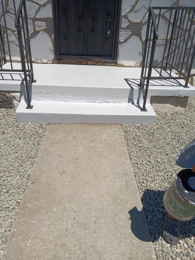 A freshly painted white concrete porch and steps, showcasing painting services by Juancho's Handyman in Salida, CO.