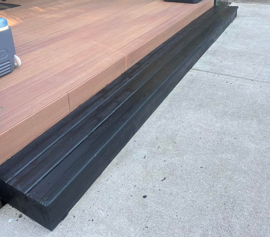 A freshly painted black wooden bench next to a deck, completed by JJT Construction in Portland, OR.