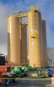Freshly painted industrial tanks with boom lifts nearby, showcasing work by WW Enroughty & Son, Inc. in Richmond, VA.