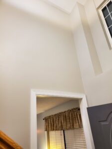 A freshly painted interior wall with a high ceiling and door frame, showcasing work by Honey Bee's Handyman Services in Hastings, NE.