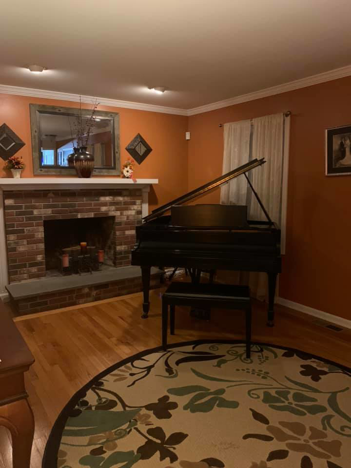 A living room with freshly painted orange walls and a brick fireplace by Connecticut Painting Group, Inc in North Haven, CT