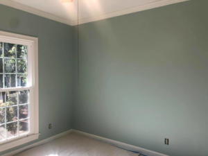 A freshly painted room with light blue walls and white trim, with drop cloths on the floor, by Your Handy Helper in Mobile, AL