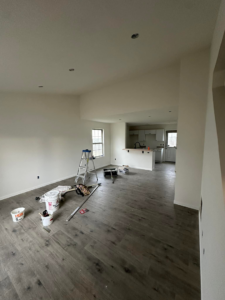 A freshly painted open-plan room with a ladder and paint buckets, showcasing a completed painting project by One Seven Painting LLC in Columbia, MO.
