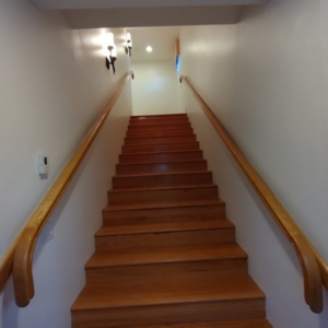 A freshly painted white staircase with wooden handrails and steps by SID Painting in West Hartford, CT.