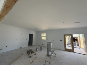 A room with freshly painted white walls and painting tools, demonstrating work by JM Drywall LLC in Dothan, AL.
