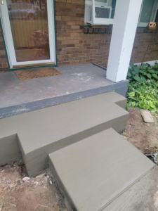 Freshly poured concrete steps leading to a residential entrance, a service by Zambrano Concrete in Duluth, MN.
